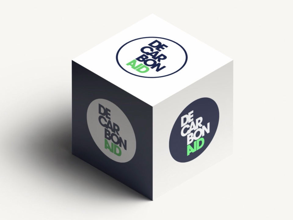Decarbonaid logo applied to three faces of a cube — white, navy, and grey colourways